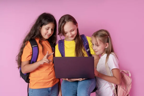 Trzy uczennice z entuzjazmem patrzą na laptopa. Koncepcja kształcenia na odległość. — Zdjęcie stockowe