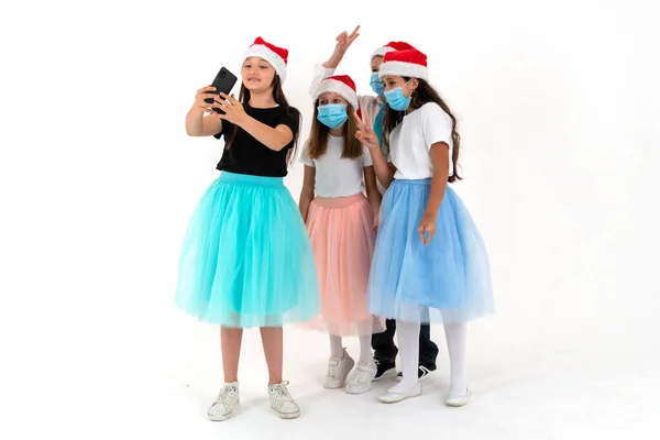 Tres chicas adolescentes y un niño sonriendo y filma un video. Navidad saludos y reuniones en línea —  Fotos de Stock