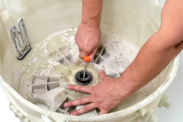 Repair of washing machines, repair of large household appliances. Repairman disassembles a washing machine for parts