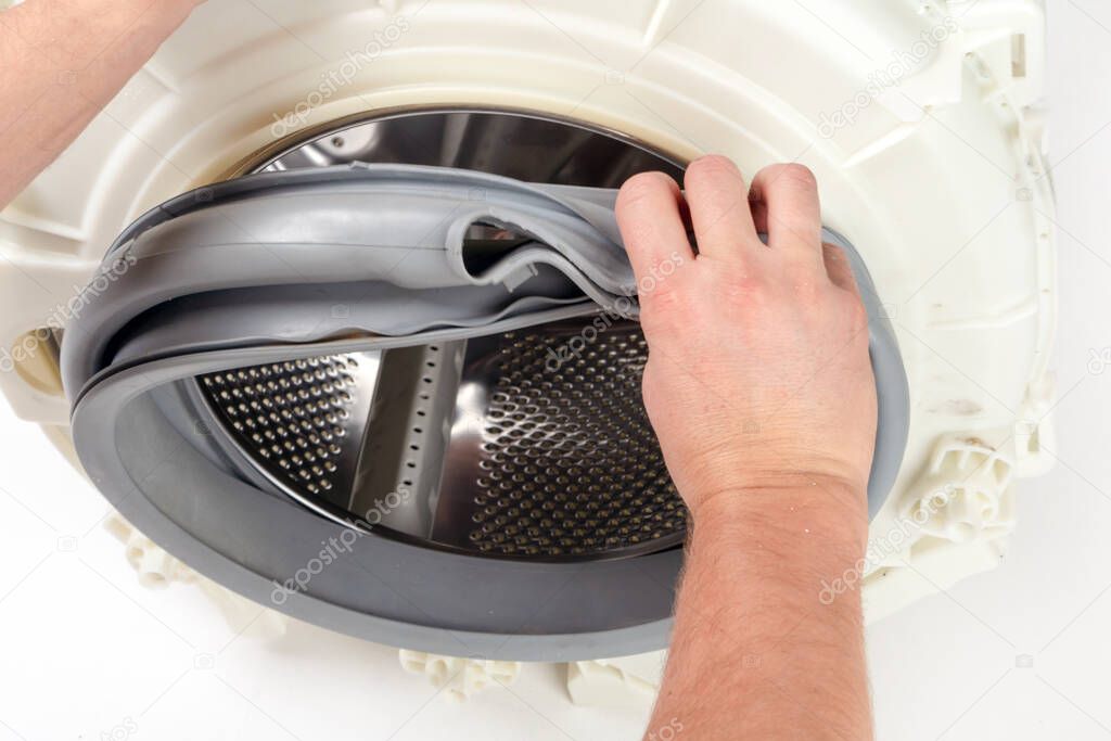 Repair of washing machines, repair of large household appliances. Repairman disassembles a washing machine for parts