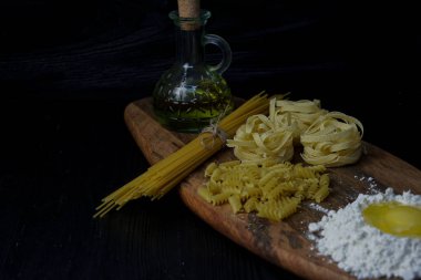 Kuru makarna çeşitli: spagetti, fusilli, tagliatelle, koyu ahşap arka plan üzerinde.