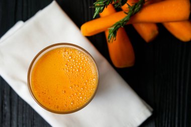 Koyu bir ağaca karşı bir bardak taze havuç suyu