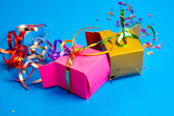 Birthday gifts, colored boxes, colored confetti inside the box, blue background
