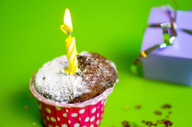 Yeşil bir arka plan üzerinde bir mum ile renkli bir kalıp lezzetli çikolatalı kek. Doğum günü pastası, tatil