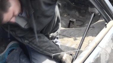 Tamir için tamirciye eski kırık araba üzerinde çalışan bir adam.