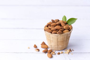 Sepetteki badem fıstıkları beyaz ahşap arka planda izole edilmiş bademler en sağlıklı fındıklardır ve en iyi beyin gıdalarından biridir..