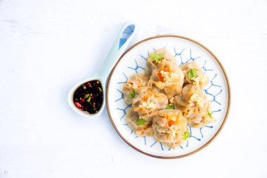 Kanton Dimsum yemek mutfağı. Sarı hamur köftesine sarılmış taze karides, sarı hamur köftesine sarılmış Çin buğulaması, beyaz ahşap zemin döşemesi, boşluk..