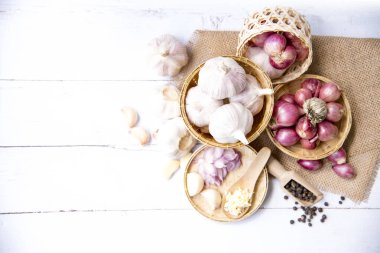 Sarımsak, soğan, karabiber, sarımsak, sarımsak karanfil, sarımsak soğanı, ahşap bir sepetin içinde beyaz ahşap bir sepet içinde soğan, bir bitki ve baharat karanfili veya yiyecek malzemeleri, yazı için yer, üst görüş. Sağlıklı gıda ya da bitkisel doğal tıp konsepti.