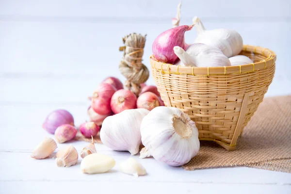 Garlic,shallot,Black pepper, fresh garlic, garlic clove, garlic bulb and Onion in a wooden basket on white wooden table, A herb and spice cloves or food ingredients, Place for text.
