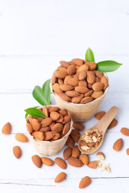Sepetteki badem fıstıkları beyaz ahşap arka planda izole edilmiş bademler en sağlıklı fındıklardır ve en iyi beyin gıdalarından biridir..