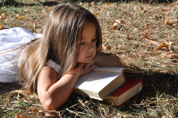 Cute Girl leżącego na ziemi w parku i czytać książkę. jesienny nastrój. Wkrótce do szkoły — Zdjęcie stockowe