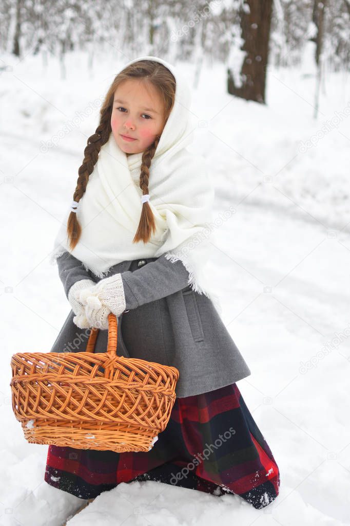 little girl in shawls in winter, looking for snowdrops
