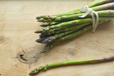 ahşap bir arka plan üzerinde taze kuşkonmaz demet. veganizm ve çiğ gıdalar
