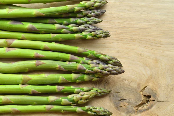 Mazzo di asparagi freschi su fondo ligneo. veganismo e cibi crudi — Foto Stock