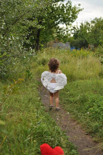 Кудрявая девушка с крыльями бежит по тропинке — стоковое фото