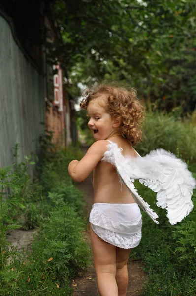 날개를 가진 곱슬 소녀는 길을 따라 실행 — 스톡 사진