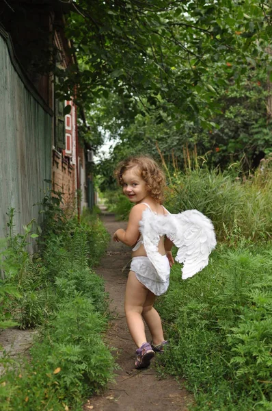 Кучерява дівчина з крилами йде по шляху — стокове фото