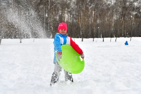Funny little girl playing with snow on a walk in the winter. Kids play outside. Winter fun concept. — Stock Photo, Image