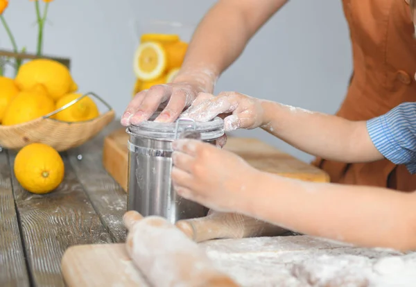 Ręce dziecka w mąkę otwartych puszek. Mąka na drewnianym stole. Żółte cytryny w tle — Zdjęcie stockowe