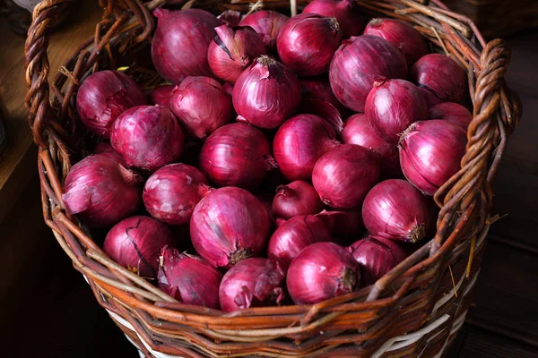 Cebolas vermelhas em uma cesta de madeira. A avitaminose de primavera — Fotografia de Stock