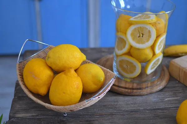 Limón en plato de madera sobre mesa de madera. Limones en rodajas. Fondo azul, cítricos, vitamina C — Foto de Stock