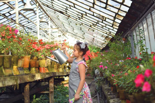 Child planting spring flowers. beautiful girl gardener plants azalea. Child taking care of plants. Girl girl watering plants from watering can. Portrait. — Stock Photo, Image