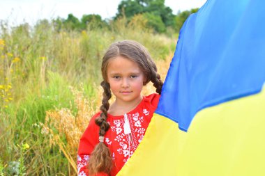 Child carries fluttering blue and yellow flag of Ukraine in field. clipart