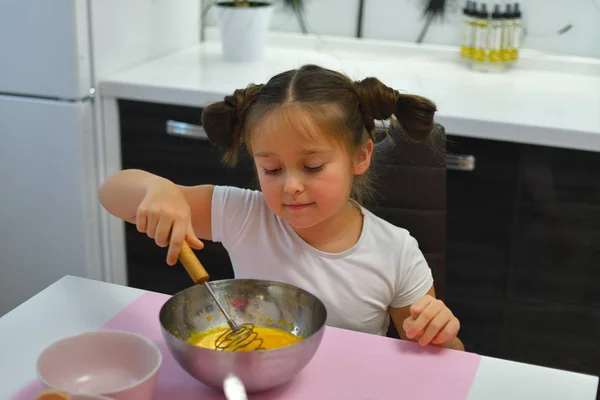 La muchacha vierte el azúcar del vaso medidor en la escudilla metálica. Niña preparando galletas en la cocina en casa. Cocinar comida casera . — Foto de Stock