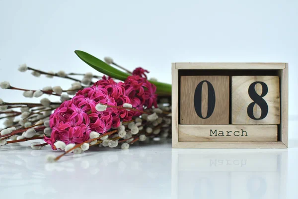 Komposition vom 8. März auf weißem Hintergrund. 8. März Text auf Holzblock-Kalender und eine Blume aus rosa Hyazinthen. Bündel von Weidenzweigen mit Kätzchen auf Hintergrund. — Stockfoto