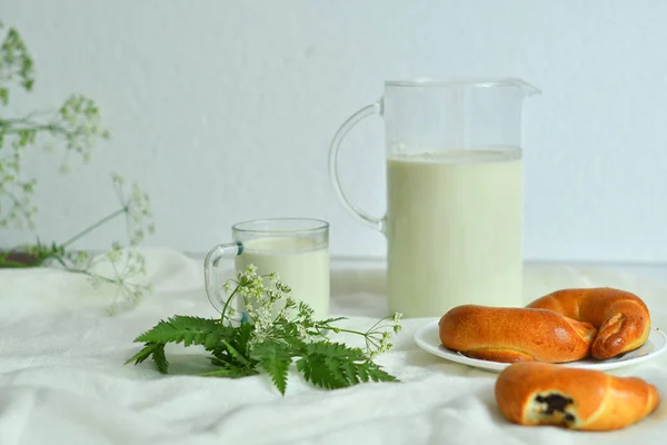Jarra de vidrio jarra de leche fresca con vidrio y croissant sobre fondo blanco. concepto de leche — Foto de Stock