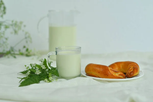 Jarra de vidrio jarra de leche fresca con vidrio y croissant sobre fondo blanco. concepto de leche —  Fotos de Stock