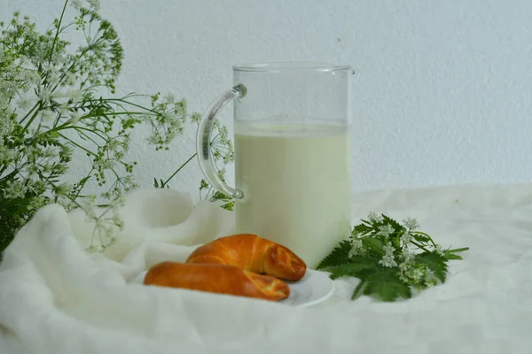 흰색 배경에 유리와 크루아상을 곁들인 신선한 우유의 유리 주전자 투수.우유 컨셉 — 스톡 사진