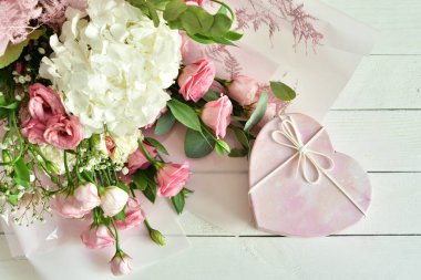 Bir buket narin pembe çiçek ve hediye ya da hediye kutusu. Çiçekler. Doğum günü, kadın ya da anneler günü için tebrik kartı. Seni seviyorum. Günaydın. Odaklan. Boşluğu kopyala..