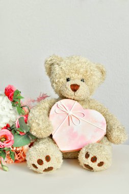 Bir buket pembe çiçek ve hediye kutusu. Oyuncak ayı. Sevgililer Günü 14 Şubat. Doğum günü, kadın ya da anneler günü için tebrik kartı. Seni seviyorum. Günaydın. Odaklan. Boşluğu kopyala..