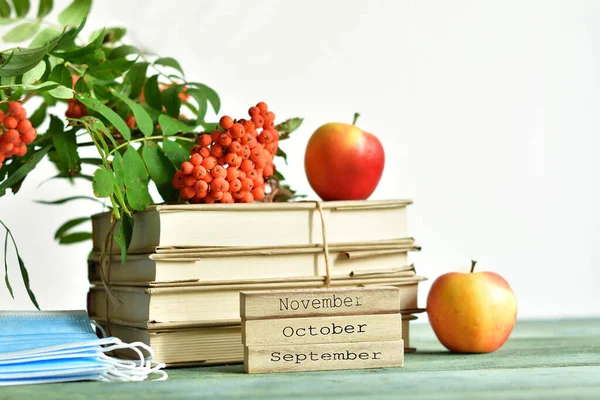 Happy teacher\'s day.books, rowan,apples and wooden blocks OCTOBER.SEPTEMBER.NOVEMBER.medical protective mask. copy space.COVID-19 Coronavirus. Distance Online learning concept.Selective focus