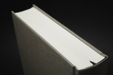 Karanlık bir arka planda ayarlanmış kalıcı siyah ipek yer imi ile bez bağlı bir kitabın üst kısmının yakın çekim görünümü.