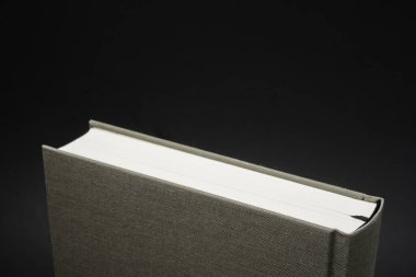 Karanlık bir arka planda ayarlanmış kalıcı siyah ipek yer imi ile bez bağlı bir kitabın üst kısmının yakın çekim görünümü.