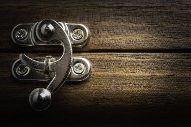 A close-up or macro look of a silver-color metal sliding lock latch installed on a polished wooden box in horizontal image format. clipart