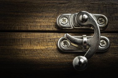 Yatay görüntü formatında cilalı ahşap kutuya takılı gümüş renkli metal sürgülü kilit mandalı bir yakın çekim veya makro görünüm.