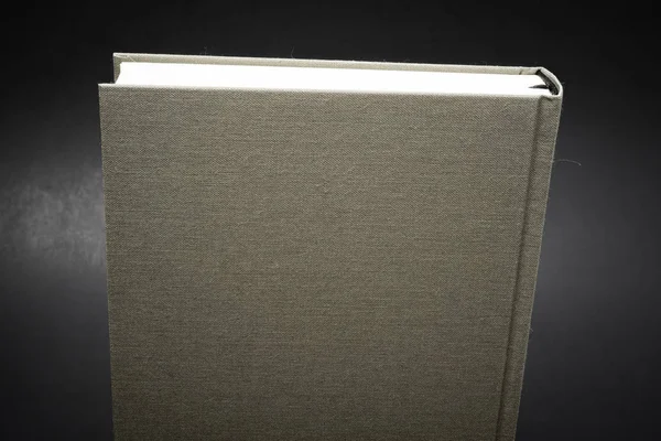 A close-up view of the top portion of a cloth-bound book with permanent black silk bookmark set on a dark background.