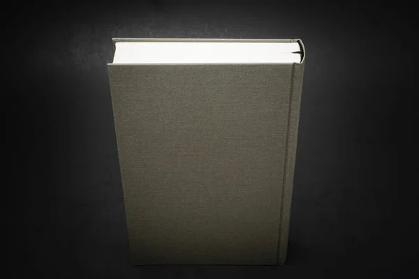 A close-up view of the top portion of a cloth-bound book with permanent black silk bookmark set on a dark background.