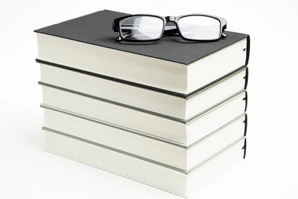 Un conjunto cuidadosamente apilado de cinco libros con gafas de lectura — Foto de Stock