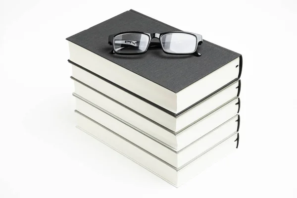 Un conjunto cuidadosamente apilado de cinco libros con gafas de lectura — Foto de Stock