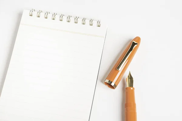 Oranžové plnicí pero s notebookem vázaným na spirálu — Stock fotografie