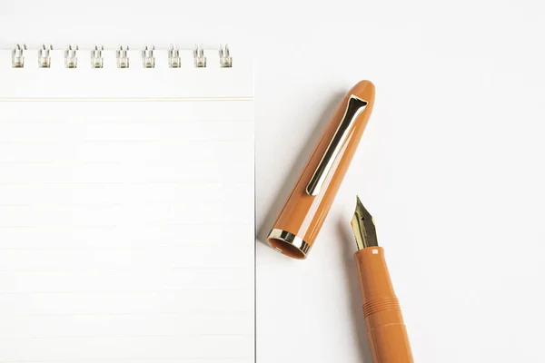Pluma estilográfica naranja con cuaderno en espiral — Foto de Stock