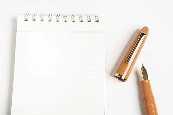 Oranžové plnicí pero s notebookem vázaným na spirálu — Stock fotografie