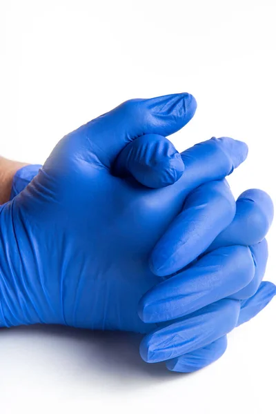 Hands wearing blue latex disposable gloves set on plain white background.