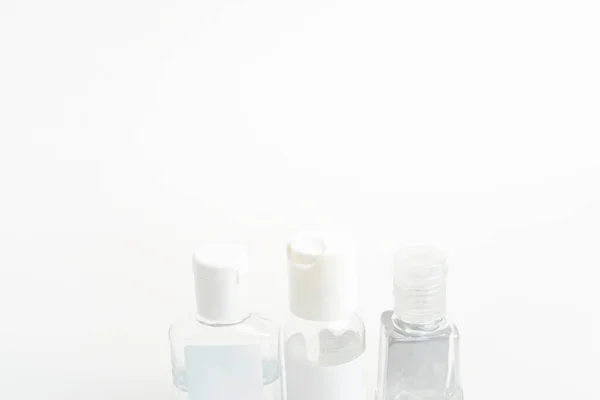 A product shot of three generic pocket-size transparent hand sanitizer plastic dispenser bottles set on a plain white background.