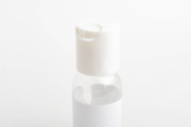 Düz beyaz arka plan üzerine kurulmuş saydam el dezenfektanı plastik bir şişenin üst beyaz kapağının yakın çekim görüntüsü..