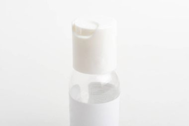 Düz beyaz arka plan üzerine kurulmuş saydam el dezenfektanı plastik bir şişenin üst beyaz kapağının yakın çekim görüntüsü..